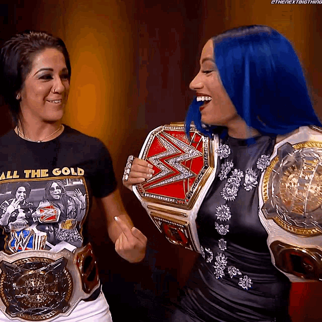 a woman wearing a shirt that says all the gold holds a wrestling belt