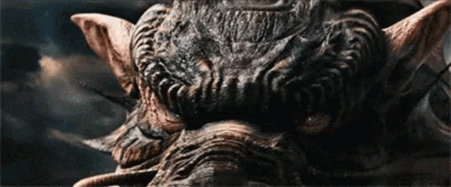 a close up of a monster 's face with horns and ears