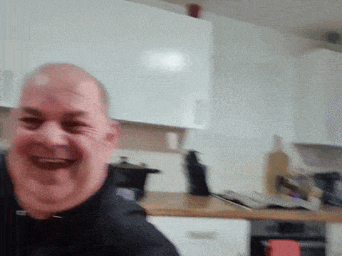 a man is laughing in a kitchen with white cabinets