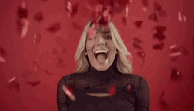 a woman is laughing while petals fall around her .