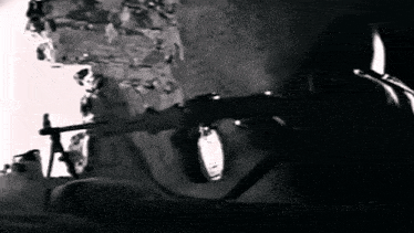a man is holding a gun in front of a brick wall