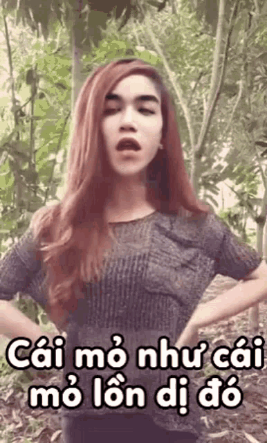 a woman with red hair is standing in the woods with her hands on her hips and making a funny face .