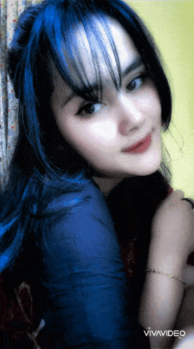 a woman with blue hair is looking at the camera with a vivavideo watermark in the corner