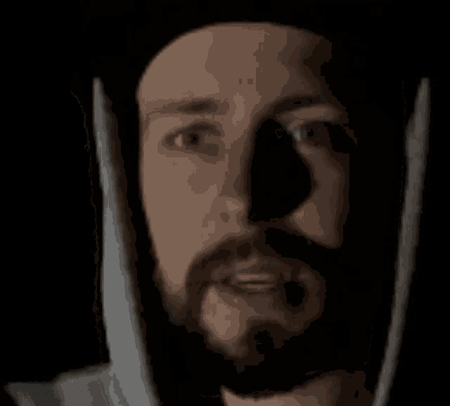 a man with a beard and a hat is making a funny face in the dark .