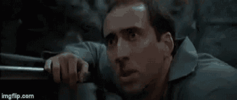 a man in a blue shirt is holding a gun in his hand .
