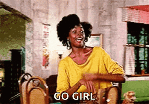 a woman in a yellow shirt is sitting at a table and says go girl