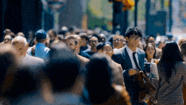 a man in a suit and tie walks through a crowd of people