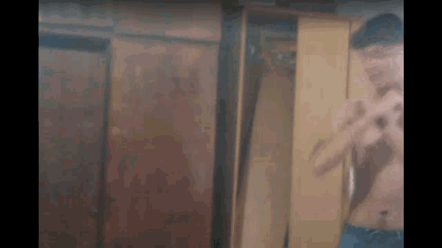 a shirtless man is taking a picture of himself in a mirror in front of a wardrobe .