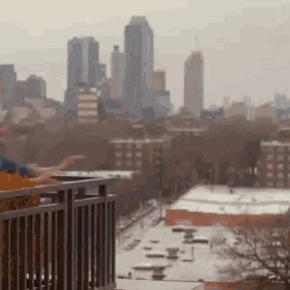 a man is standing on a balcony overlooking a city skyline