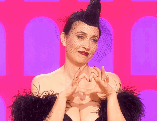 a woman with a veil on her head makes a heart with her hands