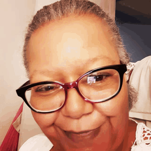a woman wearing glasses looks at the camera and smiles