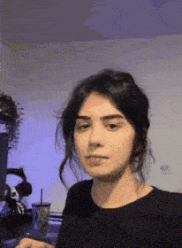 a woman in a black shirt is making a funny face while sitting in front of a computer .