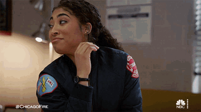 a woman wearing a chicago fire jacket is sitting at a table