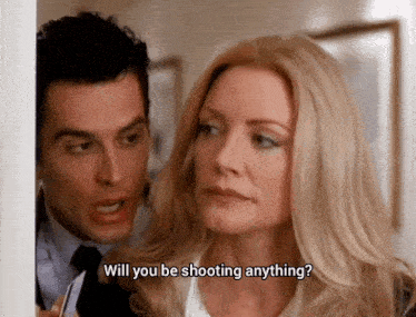 a man and woman are standing next to each other and the woman is asking the man if he will be shooting anything