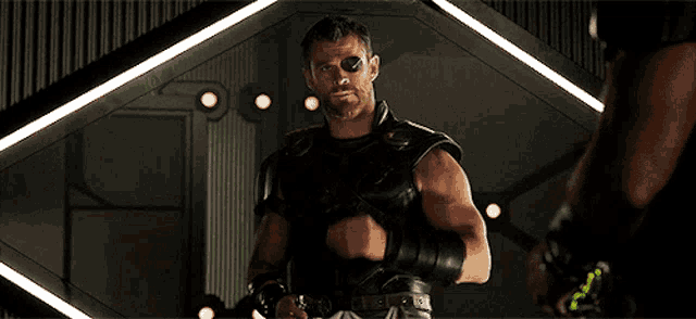 thor is standing in front of a mirror and looking at himself in the mirror .