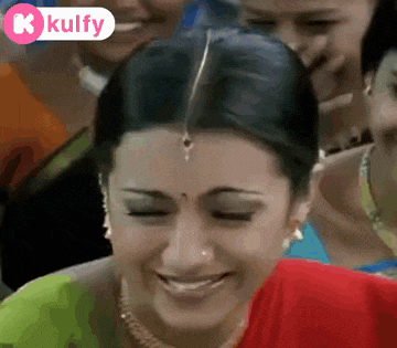 a woman in a red saree is smiling with her eyes closed .