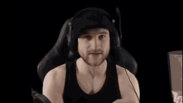 a man wearing headphones is sitting in a gaming chair and making a funny face .
