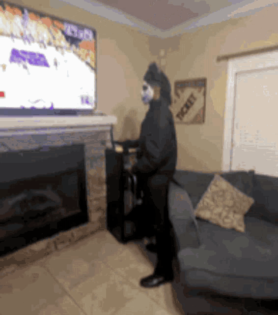 a man in a mask is standing in front of a television with a ticket sign on the wall