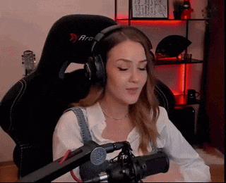 a woman wearing headphones and a white shirt is sitting in front of a microphone .