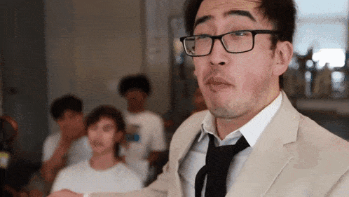a man wearing glasses and a tan suit and tie