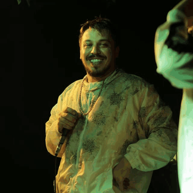 a man with a beard is holding a microphone in his hand and smiling