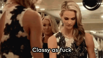a woman in a black dress is standing next to another woman in a black dress and says classy as fuck .