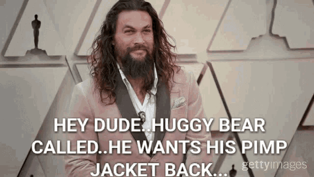 a man with long hair and a beard is wearing a pink suit and a white shirt