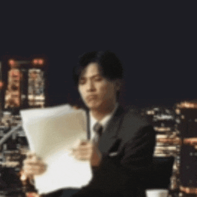a man in a suit and tie is reading a piece of paper .