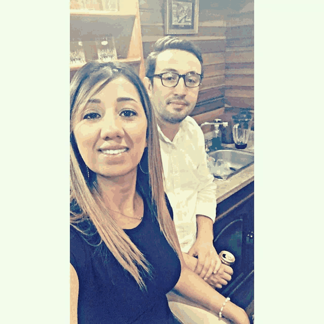 a man and a woman are posing for a photo in a kitchen