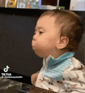 a baby is wearing a bib and making a funny face .