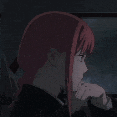 a woman with red hair is sitting in a dark room