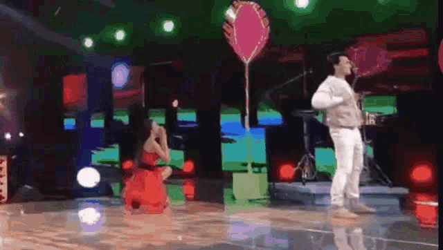 a man and a woman are dancing on a stage with a balloon in the shape of a heart