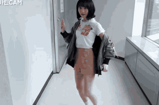a girl in a white shirt and pink shorts is walking down a hallway with pelicam written on the wall
