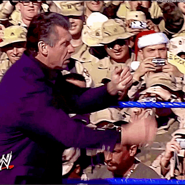 a man in a purple suit is shaking hands with a man wearing a santa hat in the crowd