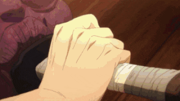 a close up of a person 's hand holding a sword on a wooden table .