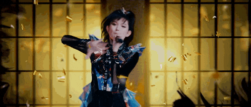 a woman is singing into a microphone while confetti falls around her