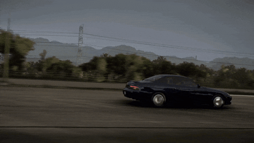 a black car is driving down a road with a white car behind it