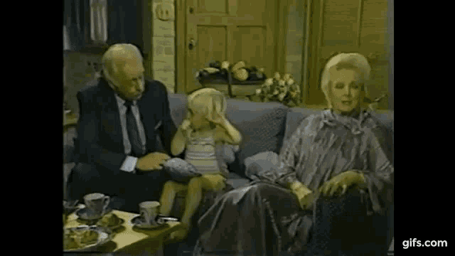 a group of people are sitting on a couch with a little girl .