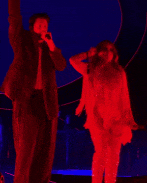 a man without a shirt is holding a microphone in his hand while dancing on stage .