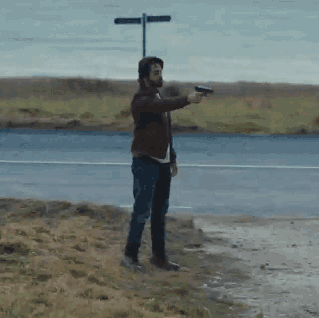 a man with a beard is pointing a gun at something in the distance