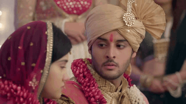 a bride and groom are sitting next to each other and the groom has a red bindi on his forehead