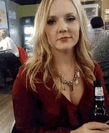a woman in a red shirt is holding a bottle of beer