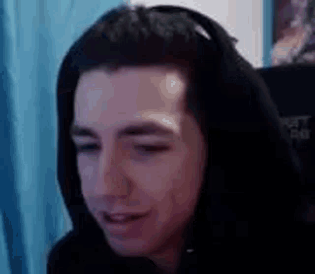 a man wearing a hoodie and headphones is smiling while sitting in front of a computer .