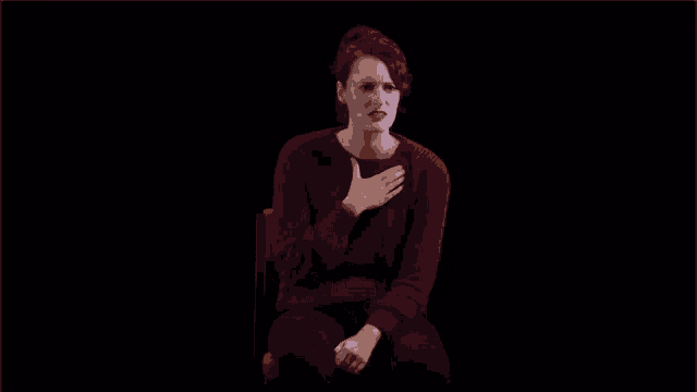 a woman in a red sweater is sitting in a chair and says the drama of it