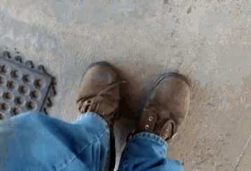 a person is standing on a concrete floor wearing brown boots
