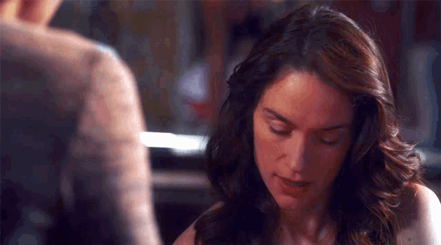 a close up of a woman looking down with a man in the background