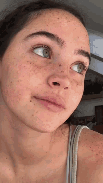 a close up of a woman 's face with freckles and blue eyes