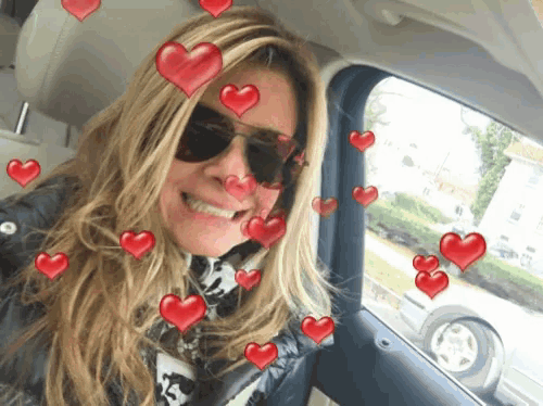a woman wearing sunglasses is smiling with red hearts around her face