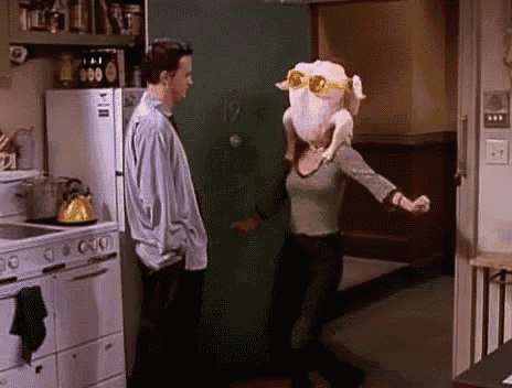 a woman with a turkey on her head is dancing in a kitchen .
