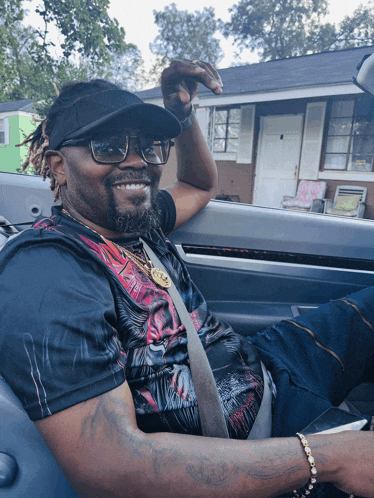 a man wearing a hat and sunglasses is sitting in the back seat of a car